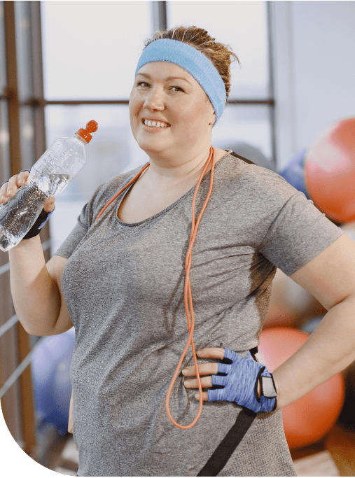 A woman holding a bottle of water and wearing gloves.