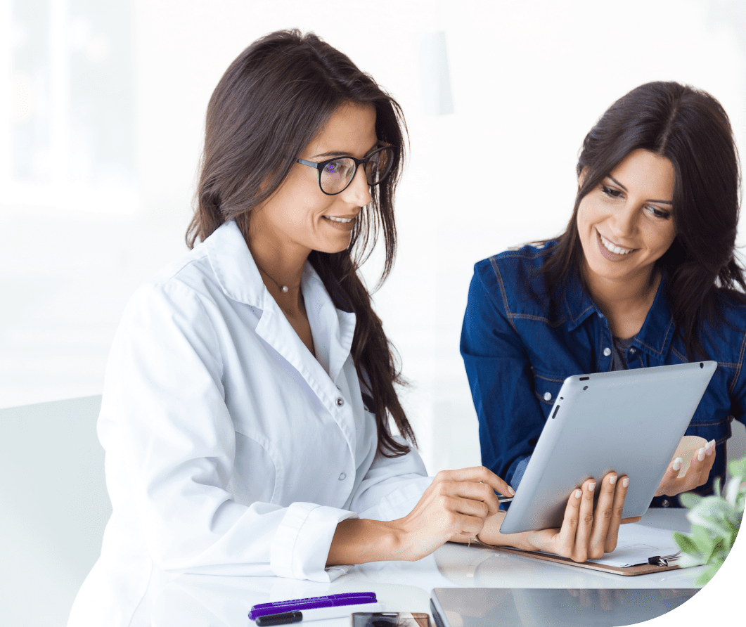 Two women sitting at a table looking at an ipad.